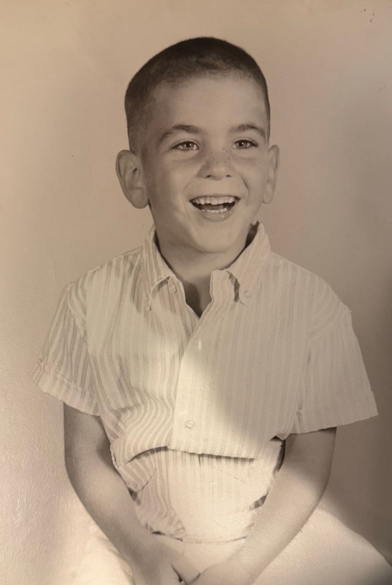 David Arnowitz as a boy, about eight, grinning in a striped shirt